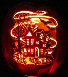 a carved pumpkin with an image of a house in the woods on it's side