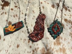 "Hand tooled and painted leather pendant necklaces to spice up that cowgirl style. The sunflower bar is on a 19\" chain. The faux turquoise painted southwest inspired pendant is on a 26\" chain. The natural freshwater pearl and classic western floral pendant is on a 24\" chain. All ready to ship and what's pictured is what you will receive." Western Stamped Brown Jewelry, Western Style Stamped Brown Jewelry, Western Brown Stamped Jewelry, Artisan Brown Hand Painted Necklace, Artisan Hand Painted Brown Necklace, Southwestern Style Hand Tooled Necklace As Gift, Handmade Western Style Necklace, Native American Headdress, Leather Pendant