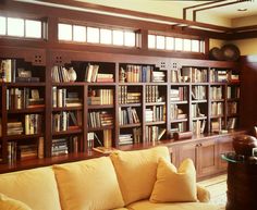 a living room filled with lots of books on top of a wooden book case next to a window