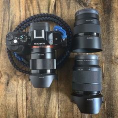 three cameras sitting next to each other on top of a wooden table with a blue cord