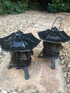 two black iron lanterns sitting on top of a rock