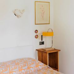 an orange and white bed in a bedroom next to a wall with pictures on it