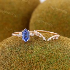 an engagement ring with a blue topazte and diamond accents sits on mossy surface