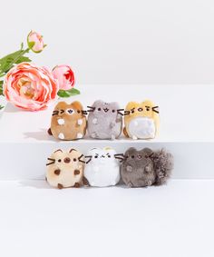 several small stuffed animals sitting on top of a white table next to a pink flower