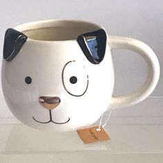 a ceramic mug with a dog's face painted on the side and a tag attached to it