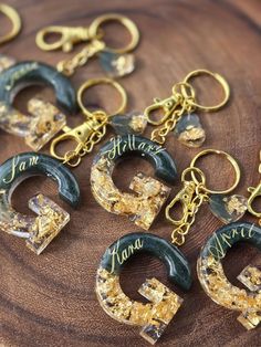 several gold and black key chains on a wooden surface with the word mama written in cursive writing