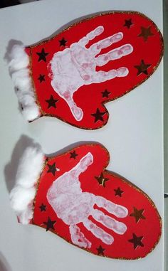 two handprinted red mittens with white hands and stars on them, sitting on top of a table