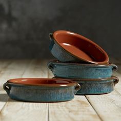 three ceramic dishes are stacked on top of each other, one is brown and the other is blue