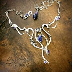 Hand forged sterling silver festoon necklace, which I've designed in the art nouveau style. Embellished with gems which I've hand selected in an analogous color theme, consisting of a rose cut lapis lazuli focal stone, with amethyst and tanzanite accent gems.  Suspended from an adjustable length chain with a tanzanite accented clasp, as well as a lapis and amethyst drop, to dangle at the back.  Chain adjusts from 16.5 to 21 inches (measuring from the top of the festoon. So, the pendant would add Analogous Color, Aa Jewelry, Festoon Necklace, Back Chain, Wire Work Jewelry, Wire Pendant, Art Nouveau Style, Handmade Jewelry Designs, Jewelry Beads