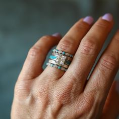 a woman's hand with two rings on it and an engagement ring in the middle