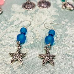 These Pierced Earrings Have Beautiful Blue Sea Glass Beads Separated With Swarovski Blue Bicones. The Starfish Dangle Is Medal And Etched Design On One Side. A Wonderful Gift! Handmade Silver Starfish Earrings, Silver Ocean-inspired Earrings With Starfish Charm, Ocean-inspired Silver Earrings With Starfish Charm, Blue Star Charm Drop Earrings, Blue Drop Earrings With Star Charm, Blue Star Charm Earrings For Gift, Blue Star Charm Earrings As Gift, Ocean-inspired Blue Jewelry With Star Charm, Ocean-inspired Nickel-free Blue Jewelry