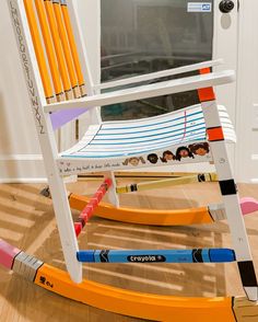 a white rocking chair with orange and blue handles on the floor in front of a door