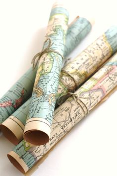 three rolled up maps are sitting next to each other on a white surface with twine