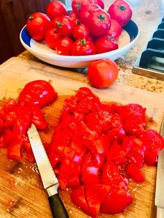 chopped up tomatoes on a cutting board next to a knife and bowl of fresh cut tomatoes