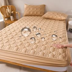 a person is pointing at an unmade bed with water droplets on the mattress top