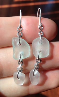 "These beautiful earrings are made from authentic seaglass combed from the beaches of northern California.  Light blue/green and white seaglass gems are laced together with intricate silver wire curls. Earwires and jumprings are made with silver-filled wire.  Each earring is approximately 1.5\" (not including the earwire length) and is a beautiful, nature-made accessory that is sure to dazzle onlookers!  Sea glass is glass from discarded bottles, lanterns, and other glasswork that has been tumbl Sea Glass Teardrop Earrings For Beach, Silver Recycled Glass Beach Earrings, Beach Earrings In Silver With Recycled Glass, Beach Silver Earrings With Recycled Glass, Silver Recycled Glass Earrings For The Beach, Handmade Sea Glass Dangle Earrings, Beach Sea Glass Earrings With Ear Wire, Beach Earrings With Sea Glass And Ear Wire, Beach Earrings With Recycled Glass And Ear Wire