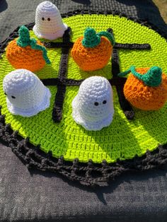 crocheted pumpkins and ghost decorations on a green tablecloth with black trim