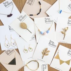 many different types of earrings are on the table next to some brochures and cards