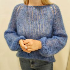 a woman is wearing a blue sweater and holding her hands in her pockets while looking into the mirror