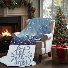 a blanket that says let it snow next to a chair and christmas tree with presents