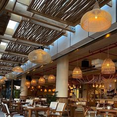 a restaurant with wooden tables and chairs, chandeliers hanging from the rafters