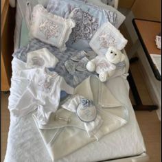 a bed with white sheets and pillows on top of it next to a drawer filled with stuff