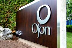 a large sign that says ojon on it in front of some bushes and trees