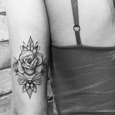 black and white photo of two women's legs with tattoos on their arms, one has a rose