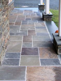 a stone walkway with benches on each side and grass in the back ground behind it