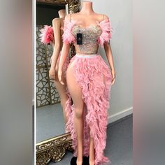 a mannequin dressed in pink feathers stands next to a mirror