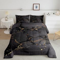 a bed with black and gold paint splattered on the comforter, pillows and pillow cases