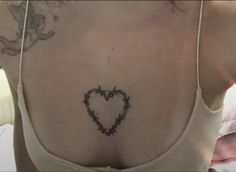 the back of a woman's bra with barbed wire around her neck and heart tattoo