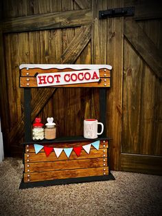 an old fashioned hot chocolate stand with flags and bunting on the top, sitting in front of a wooden wall