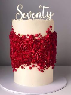 a white cake with red flowers and the word seventy on top