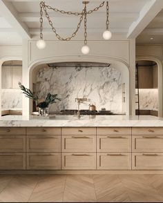 a large kitchen with marble counter tops and wooden cabinetry, along with hanging lights