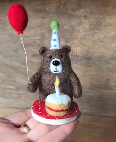 a teddy bear with a birthday hat on top of a cupcake and a balloon