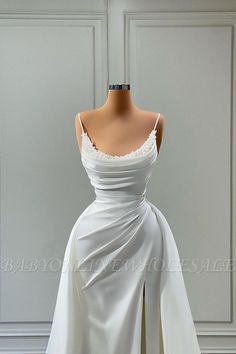 a white wedding dress on display in front of a wall