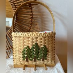 a woven basket with trees on it sitting on a towel next to a wooden rack