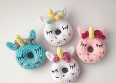 four crocheted unicorn donuts are shown in different colors