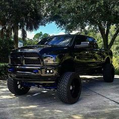 a large black truck parked on top of a driveway