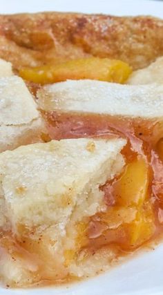 two pieces of bread with peaches and powdered sugar on top sitting on a white plate