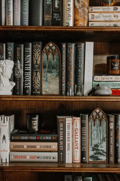 several books are stacked on top of each other in a bookcase with statues and sculptures