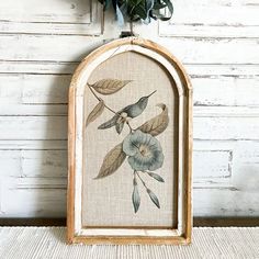 an old frame with flowers and leaves painted on the inside is hanging on a wall