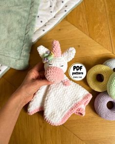 a person holding a stuffed animal next to some crocheted items on a wooden floor