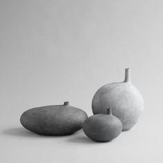 three gray vases sitting next to each other on a white surface with no one around them