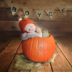 a baby sleeping in a pumpkin wearing a knitted hat