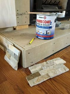 a can of primecoat next to some tiles on the floor in front of a fireplace