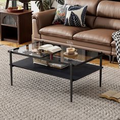 a living room with a couch, coffee table and books on the floor in front of it