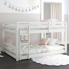 a white bunk bed sitting in a bedroom next to a rug on the wooden floor