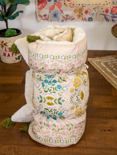 a pile of blankets sitting on top of a wooden table next to a potted plant